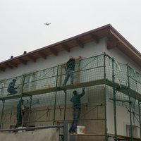 Maler auf einem Gerüst beim Fassadenstreichen